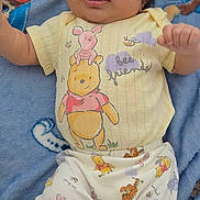 Freddy joined the competition — help win amazing prizes! baby, infant, child, portrait, lying_down, smiling, tongue_out, cartoon_clothing, yellow_shirt, patterned_pants, winnie_the_pooh, paw_patrol, blanket, blue_background, indoor, full_body, face, hands, feet, cute