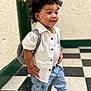 toddler, child, curly_hair, white_shirt, denim_jeans, sneakers, backpack, smile, indoor, checkered_floor, black_and_white_floor, standing, happy, casual_clothing, person, cute, young_child, portrait, fashion, confident