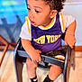 toddler, child, curly_hair, high_chair, purple_clothing, new_york, socks, nike, indoor, wooden_floor, black_chair, curious, seated, baby, cute, portrait, expression, hands, looking_away, young_child