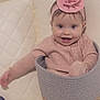 baby, child, smiling, pink_clothing, headband, flower, basket, couch, quilted, toy, colorful, indoor, happy, cute, infant, person, seated, small_person, home, playtime