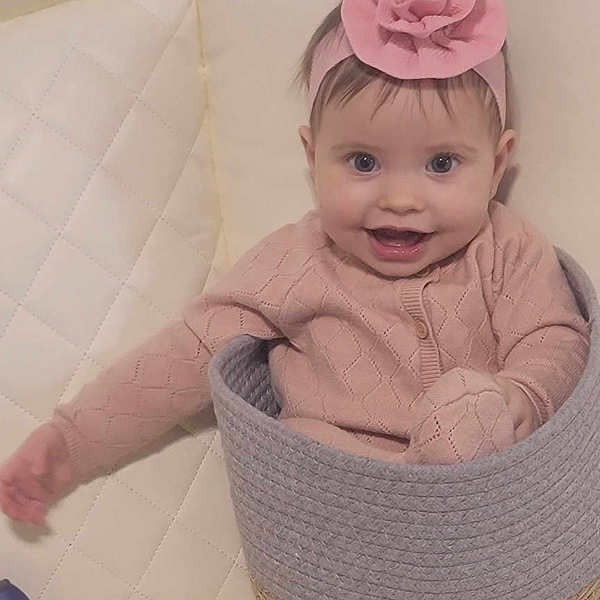 Mya joined the competition — help win amazing prizes! baby, basket, child, colorful, couch, cute, flower, happy, headband, home, indoor, infant, person, pink_clothing, playtime, quilted, seated, small_person, smiling, toy