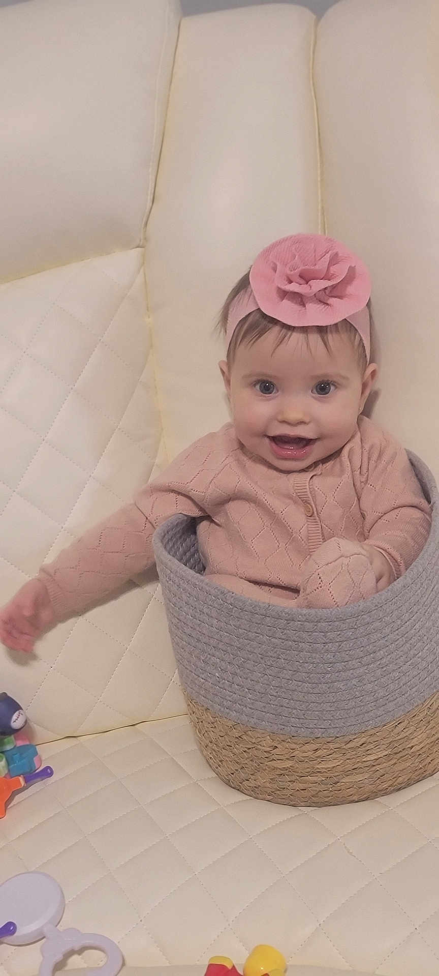 Mya joined the competition — help win amazing prizes! baby, child, smiling, pink_clothing, headband, flower, basket, couch, quilted, toy, colorful, indoor, happy, cute, infant, person, seated, small_person, home, playtime