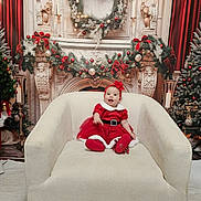 Mya is registered to the contest to win money with this photo: baby, child, christmas, holiday, red_dress, headband, armchair, wreath, garland, candles, decorations, festive, smiling, indoor, celebration, seasonal, happy, portrait, christmas_tree, background