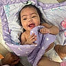 baby, blanket, bow, child, cozy, cute, diaper, face, hand, happy, indoors, infant, joyful, lying_down, person, playful, purple, skin, smiling, soft