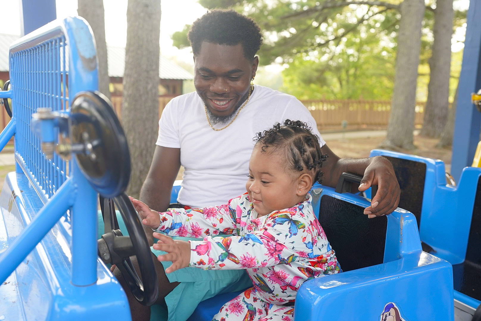 Sirena is registered to the contest to win money with this photo: automotive_exterior, blue, child, city, community, event, fun, happy, joy, leisure, motor_vehicle, people, person, play, recreation, sitting, summer, t_shirt, toddler, travel