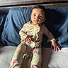 baby, child, infant, portrait, sitting, lying_down, floral_outfit, onesie, blue_pillow, bed, bedroom, wooden_headboard, indoors, face, eyes, wide_eyed, calm, clothing, natural_light, photography