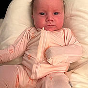 Callie joined the competition — help win amazing prizes! baby, infant, pink_onesie, cushion, soft_fabric, indoor, person, child, face, portrait, cute, newborn, young_child, expression, seated, relaxed, closeup, skin, head, small