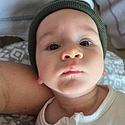 Zayn joined the competition — help win amazing prizes! baby, infant, face, headwear, knit_cap, onesie, arm, blanket, closeup, portrait, child, skin, person, indoor, resting, cute, young, expressionless, soft_lighting, newborn