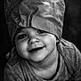 child, baby, toddler, portrait, black_and_white, smile, big_hat, eyes, cheeks, close_up, soft_lighting, fabric, texture, cute, expression, candid, clothing, adorable, studio_style, high_grain