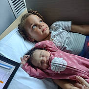 Infinitee is registered to the contest to win money with this photo: child, baby, newborn, siblings, bed, blanket, pink_onesie, sleeping, curly_hair, striped_shirt, hand_holding, indoors, portrait, cozy, resting, cute, peaceful, family, toddler, cuddling