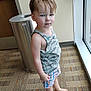 Rein is registered to the contest to win money with this photo: barefoot, blue_eyes, carpet, child, clothing, face, hair, indoor, light, person, plaid, reflection, serious_expression, shorts, skin, standing, tank_top, toddler, trash_can, window