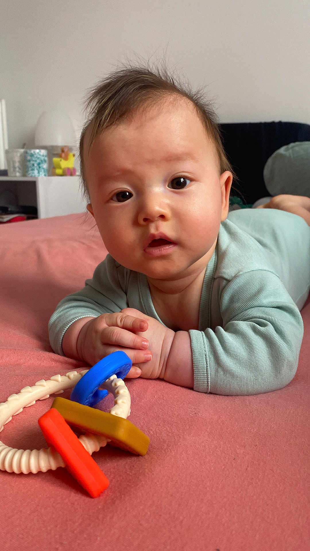 Oscar participe au concours pour gagner de l'argent avec cette photo : baby, infant, tummy_time, toy, rattle, bed, onesie, portrait, close_up, eyes, hands, skin, hair, cute, indoor, nursery, pink_bed, expression, playtime, child