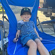 Joshua joined the competition — help win amazing prizes! child, boy, smiling, blue_chair, cap, under_armour, shorts, tshirt, outdoor, grass, stick, suburban, vehicle, truck, street, sunlight, summer, happy, casual, relaxing
