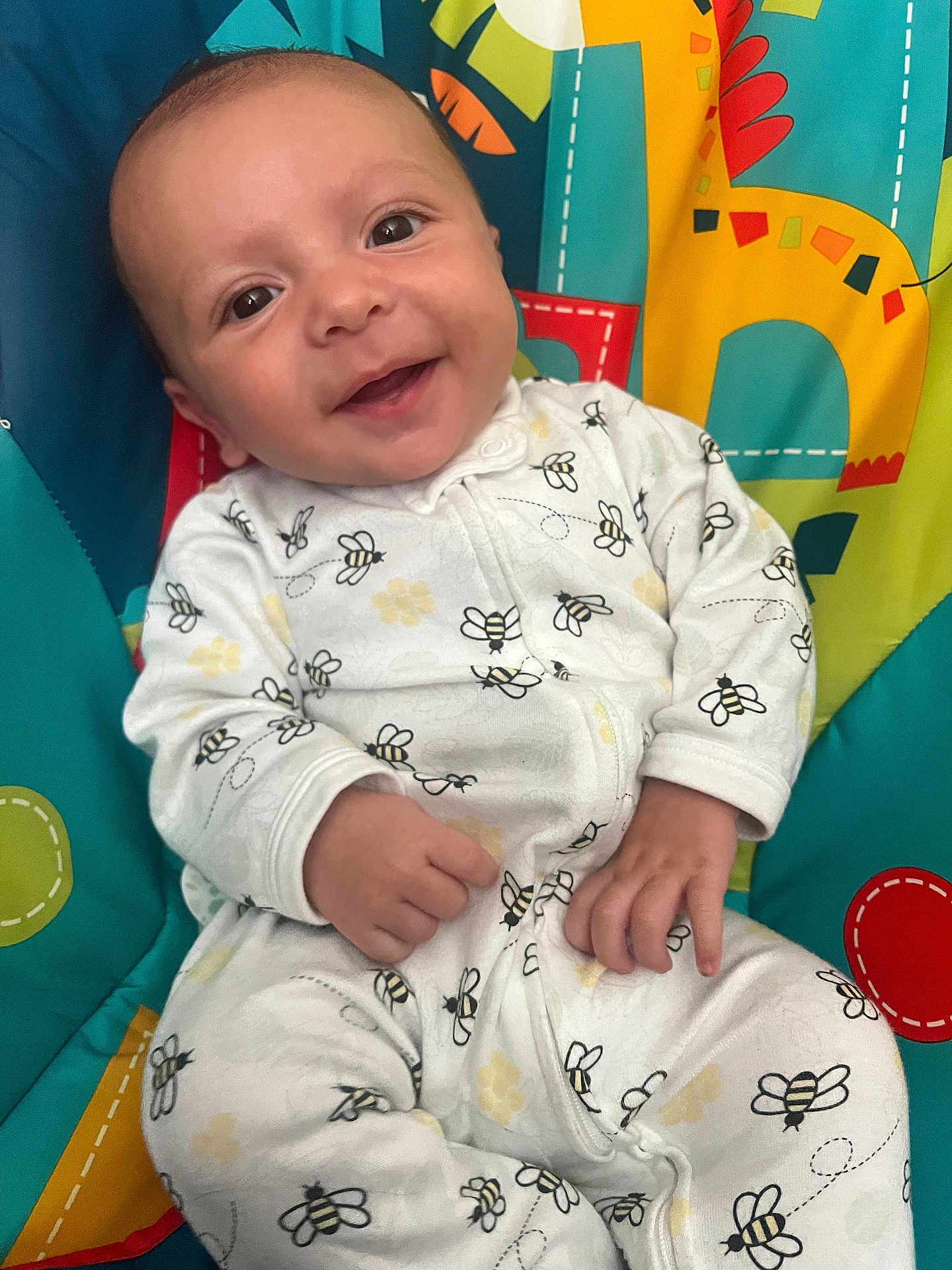 Roman joined the competition — help win amazing prizes! baby, smiling, infant, onesie, bee_pattern, play_mat, colorful, animal_design, cute, hands, face, happy, child, seated, indoors, clothing, person, portrait, young_child, joy