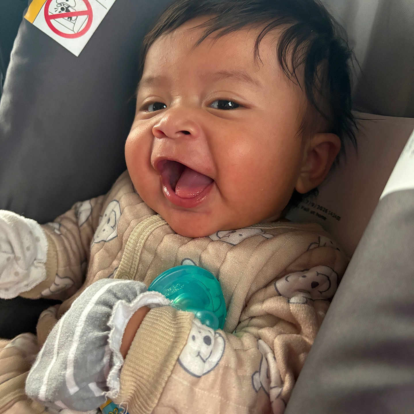 Jasiel is registered to the contest to win money with this photo: baby, infant, smiling, pajamas, mittens, car_seat, formula_bottle, happy, closeup, face, child, cute, indoor, person, infant_formula, warning_label, expression, clothing, comfort, seat