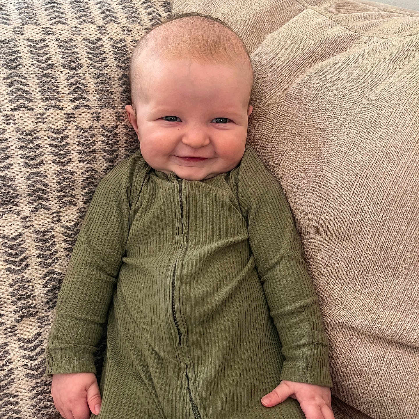 Cole joined the competition — help win amazing prizes! baby, child, smile, green_onesie, couch, cushion, indoor, portrait, happy, infant, person, face, seated, cozy, home, fabric, texture, cute, young, relaxed