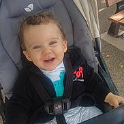 Gabin participe au concours pour gagner de l'argent avec cette photo : toddler, child, stroller, smiling, happy, outdoor, clothing, seatbelt, jacket, baby, person, face, cute, playful, sitting, daylight, bench, hair, hands, park