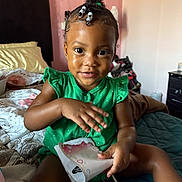 Loyalty joined the competition — help win amazing prizes! toddler, child, bedroom, bed, green_dress, person, curly_hair, beads, package, smile, skin, furniture, blanket, pillow, indoors, cute, young_child, sitting, playful, portrait