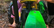 Atlas is registered to the contest to win money with this photo: child, baby, toddler, toy_tractor, outdoor, garden, play, green, vehicle, person, hands, sunlight, grass, leaves, footwear, clothing, face, expression, fun, family