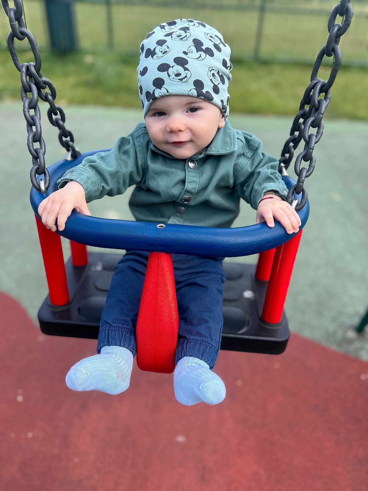 Andrei is registered to the contest to win money with this photo: baby, child, swing, playground, hat, mickey_mouse, clothing, blue, red, outdoor, fun, smile, person, toy, seat, chain, park, cute, happy, infant