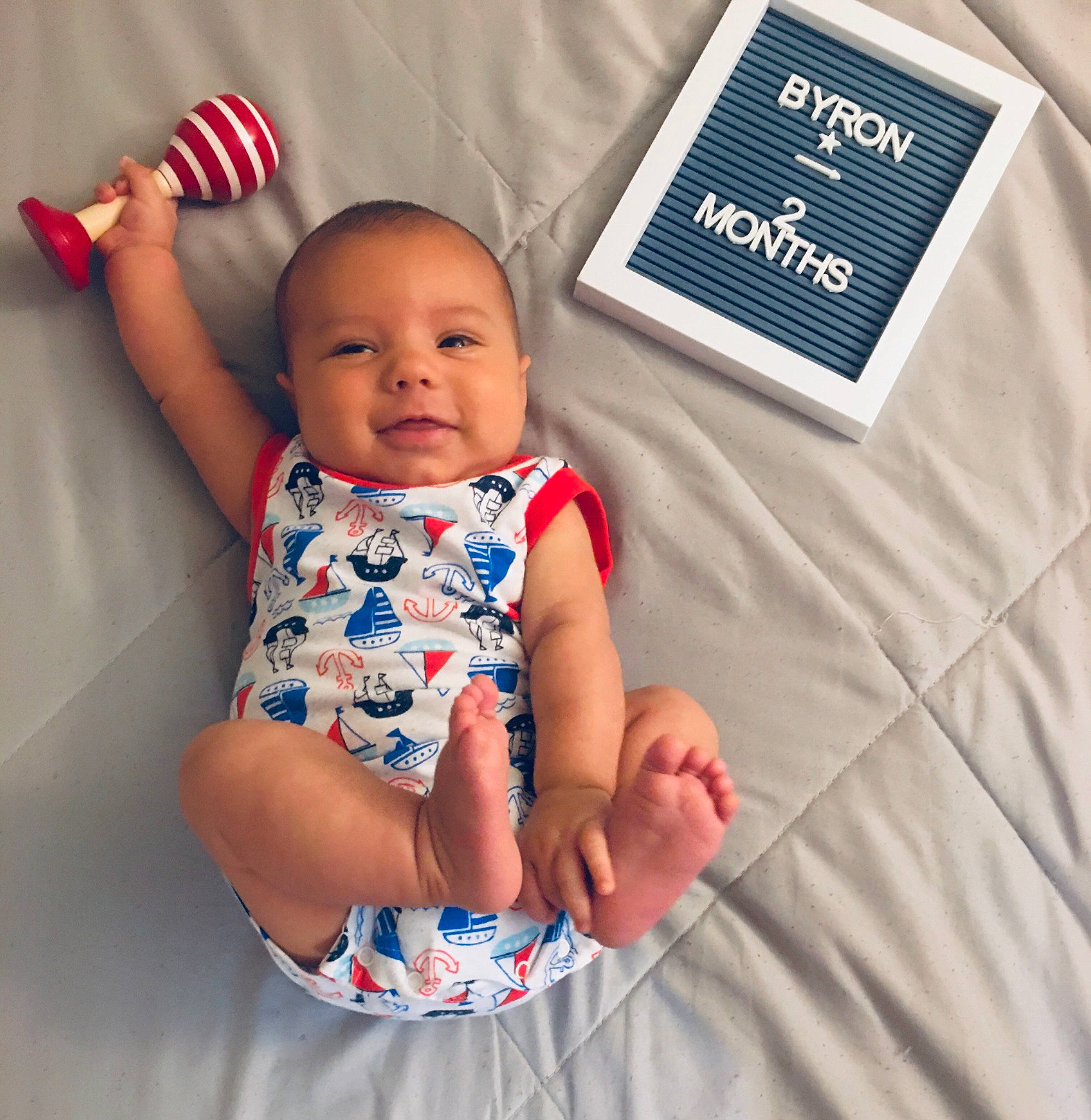 Byron is registered to the contest to win money with this photo: baby, baby_toddler_clothing, child, electric_blue, event, finger, gesture, hand, happy, linens, people, person, product, skin, sleeve, smile, t_shirt, textile, thumb, toddler