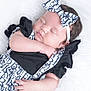 baby, sleeping, infant, headband, bow, black_clothing, white_background, soft_texture, cute, peaceful, portrait, newborn, child, adorable, hand, face, closed_eyes, fluffy, fashion, resting