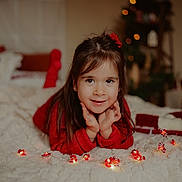 Alyssa a rejoint le concours — aidez-le/la à gagner de superbes lots ! child, girl, smile, red_sweater, hands, face, string_lights, candy_cane, blanket, bed, holiday, christmas_tree, decor, cozy, indoors, portrait, cute, happy, warm, soft_focus