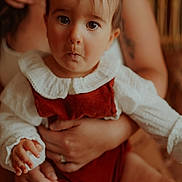Romane participe au concours pour gagner de l'argent avec cette photo : baby, child, infant, face, expression, pigtails, hands, adult, holding, clothing, white, red, cute, indoor, portrait, skin, eyes, mouth, sitting, furniture