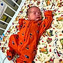 Enzo is registered to the contest to win money with this photo: newborn, baby, sleeping, crib, hospital, orange_onesie, blanket, cartoon_dogs, autumn_leaves, medical_tube, peaceful, infant, bed, cute, child, indoors, resting, person, soft, young
