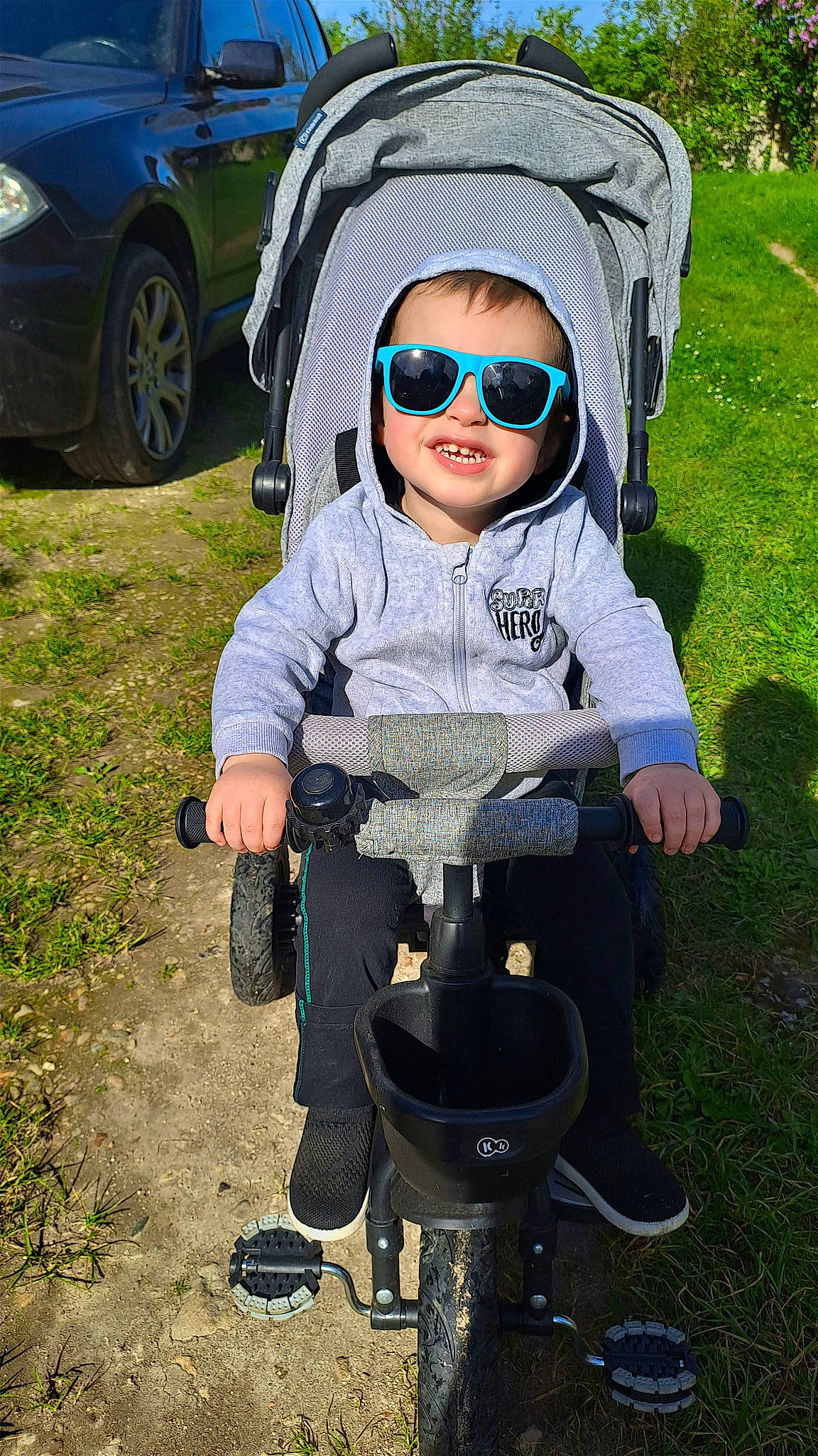 Tylio a rejoint le concours — aidez-le/la à gagner de superbes lots ! automotive_lighting, automotive_tire, baby_carriage, cap, electric_blue, eyewear, goggles, grass, headgear, person, personal_protective_equipment, plant, shoe, sneakers, sunglasses, tire, toddler, vehicle, vehicle_door, vision_care
