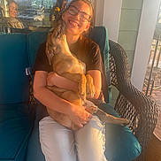 Hank joined the competition — help win amazing prizes! affection, black_shirt, casual_clothing, cushion, daylight, dog, glasses, happy, home, outdoor, pet, porch, reflection, seated, smiling, sunlight, white_pants, wicker_chair, window, woman