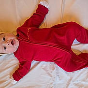 Helena participe au concours pour gagner de l'argent avec cette photo : baby, infant, headband, red_onesie, footed_pajamas, lying_down, white_sheet, bed, mouth_open, eyes_open, cute, portrait, newborn, mittens, small_hands, soft_fabric, candid, indoors, smile_like_expression, baby_clothing