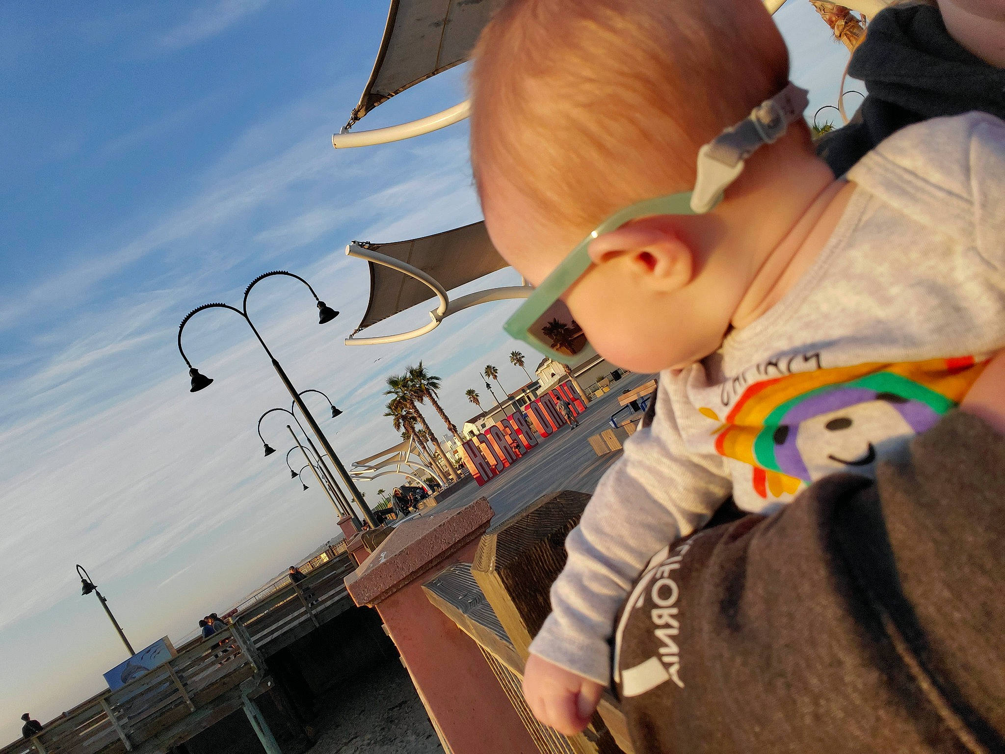 Aspen is registered to the contest to win money with this photo: baby, child, city, cloud, eyewear, fun, grass, happy, leisure, person, play, recreation, sitting, sky, street_light, sunglasses, t_shirt, toddler, tourism, travel