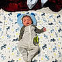 baby, newborn, sleeping, blanket, striped_clothing, hat, bed, pillow, pattern, dog_print, infant, cute, cozy, soft, child, rest, peaceful, indoors, laying_down, comfortable