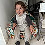 toddler, child, onesie, animal_costume, armchair, indoor, floor_tiles, curtain, television, chair, patterned_fabric, happy, surprised, sitting, furniture, person, cozy, cute, smiling, home