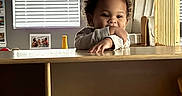 Maurice joined the competition — help win amazing prizes! child, toddler, smiling, face, curly_hair, wooden_shelf, toy_plane, window_blinds, arm_resting, indoor, furniture, cozy, home, natural_light, person, childhood, playroom, casual, happy, young