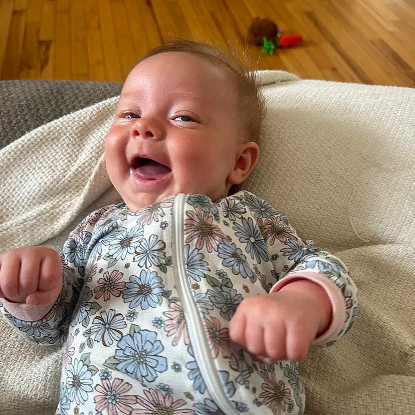 Nova joined the competition — help win amazing prizes! baby, babylaughing, clothing, coat, couch, face, furniture, happy, hardwood, head, jacket, laughing, newborn, pants, person, photography, portrait, quilt, smile, wood