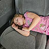 child, sleeping, car_seat, pink_shirt, patches, fries, strawberry, hair, face, arm, relaxed, interior, vehicle, seat, clothing, casual, young, resting, daylight, portrait