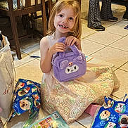 Mattie joined the competition — help win amazing prizes! activity_sheet, background, child, dog_print, dress, floor, furniture, gift_wrap, girl, handbag, happy, indoor, legs, person, presents, purple_bag, shoes, smile, tile_floor, toy