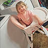 Olivia is registered to the contest to win money with this photo: toddler, child, high_chair, smiling, indoor, laundry_room, washing_machine, dryer, floor, door, household_items, clothing, happy, person, furniture, plastic, messaging_app, screen_overlay, home, portrait