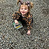 toddler, child, girl, leopard_print, hair_bows, jacket, gravel, sidewalk_chalk, container, outdoor, crouching, smiling, cute, playful, person, young_child, daylight, fashion, ground, nature