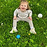 child, toddler, grass, greenery, dandelion, flower, ball, toy, smiling, happy, outdoor, nature, playing, casual_clothing, pink_bow, shoes, sitting, sunlight, portrait, cute