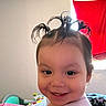Marisol is registered to the contest to win money with this photo: toddler, child, smile, hair, ponytails, indoor, window, red_cloth, toy, happy, face, person, cute, playful, young_child, baby, clothing, room, daylight, expression