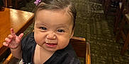 Marisol joined the competition — help win amazing prizes! black_shirt, blanket, carpet, child, cute, dining, funny_face, furniture, hair_clip, high_chair, indoor, people, person, purple_flower, reaching_hand, restaurant, smiling, table, toddler, wooden_chair