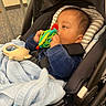 Yael is registered to the contest to win money with this photo: baby, child, stroller, toy, blue_blanket, infant, indoors, car_seat, cute, young_child, holding, playing, closeup, face, person, warm_clothing, baby_toy, seated, headrest, carriage