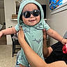 arm, baby, casual, child, curtain, cute, donut_print, furniture, happy, holding, hoodie, human, indoor, living_room, person, pizza_print, shirt, smile, sunglasses, window