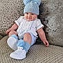baby, child, hat, pom_pom, socks, shoes, couch, pillow, knitwear, white_shoes, blue_hat, smiling, cute, indoor, portrait, sitting, cozy, fashion, infant, plush