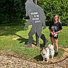 Trinity joined the competition — help win amazing prizes! casual_clothing, dog, glasses, grass, gravel, leash, nature, outdoor, pet, portrait, shadow, shorts, sign, smile, summer, sunlight, tree, tshirt, woman, wood