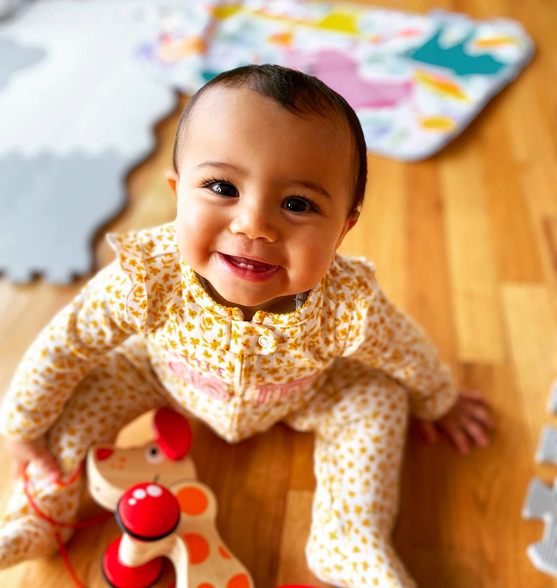 Gianna is registered to the contest to win money with this photo: baby, baby_toddler_clothing, cheek, child, chin, dress, eye, flooring, happy, iris, joy, neck, nose, pattern, person, sitting, skin, sleeve, smile, toddler