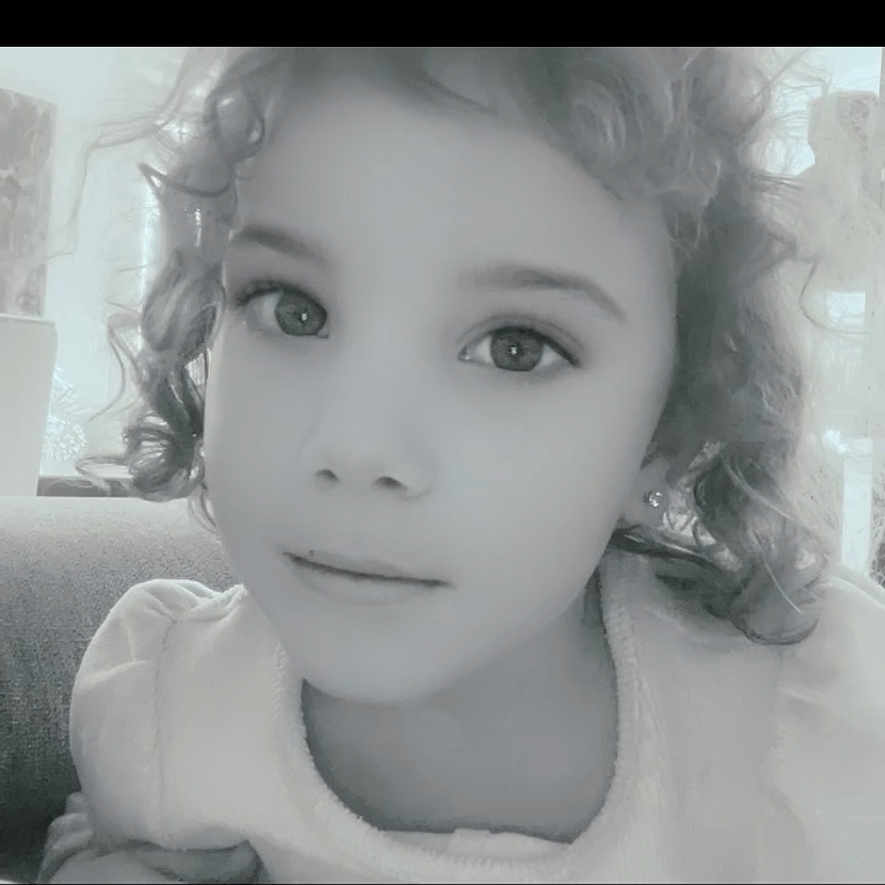 Layana participe au concours pour gagner de l'argent avec cette photo : black_and_white, calm, casual, child, closeup, couch, curly_hair, cute, earrings, expression, eyewear, face, head_and_shoulders, indoor, person, portrait, resting, smile, soft_lighting, young